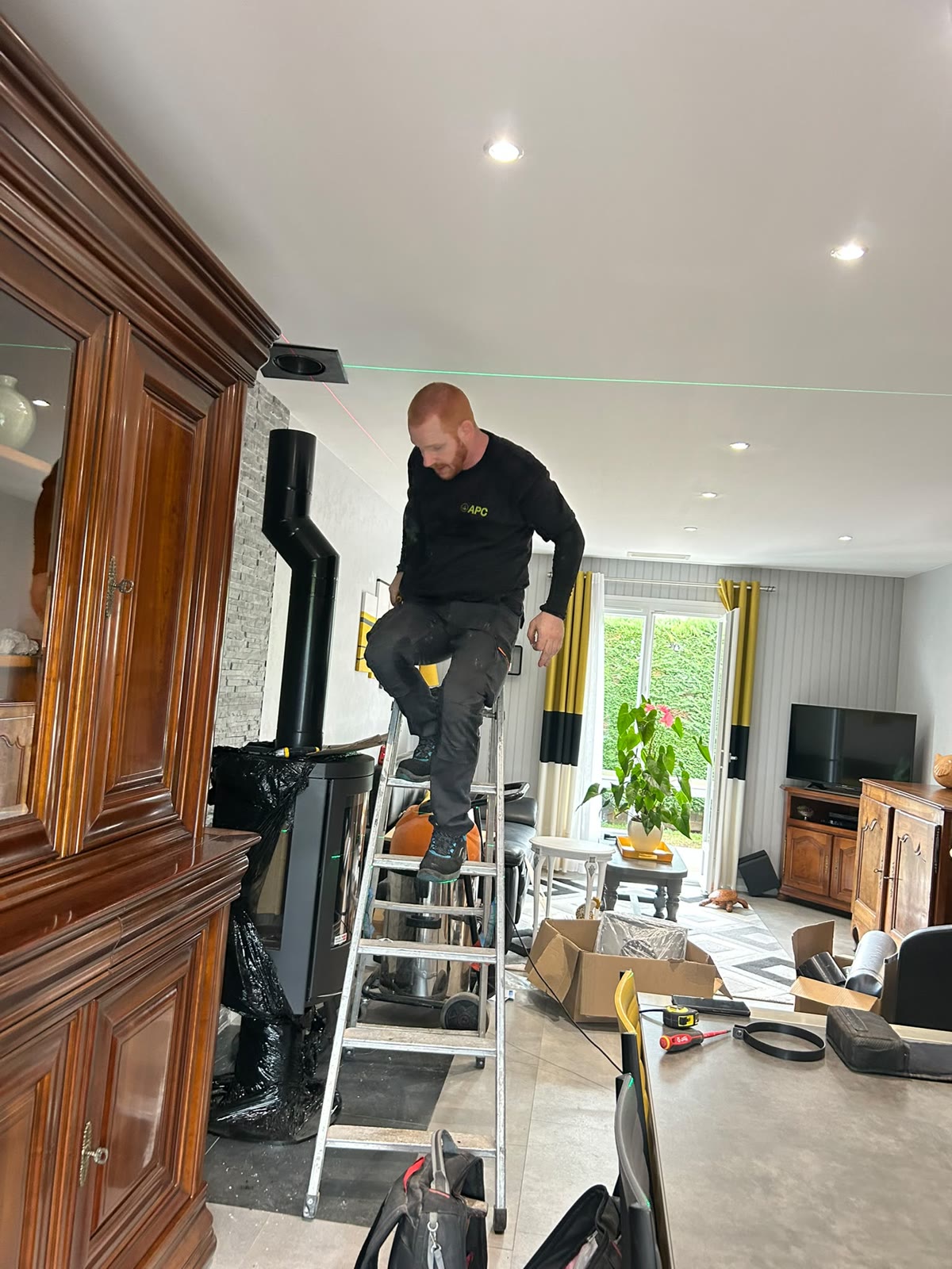 Technicien APC raccordant le conduit noir au plafond