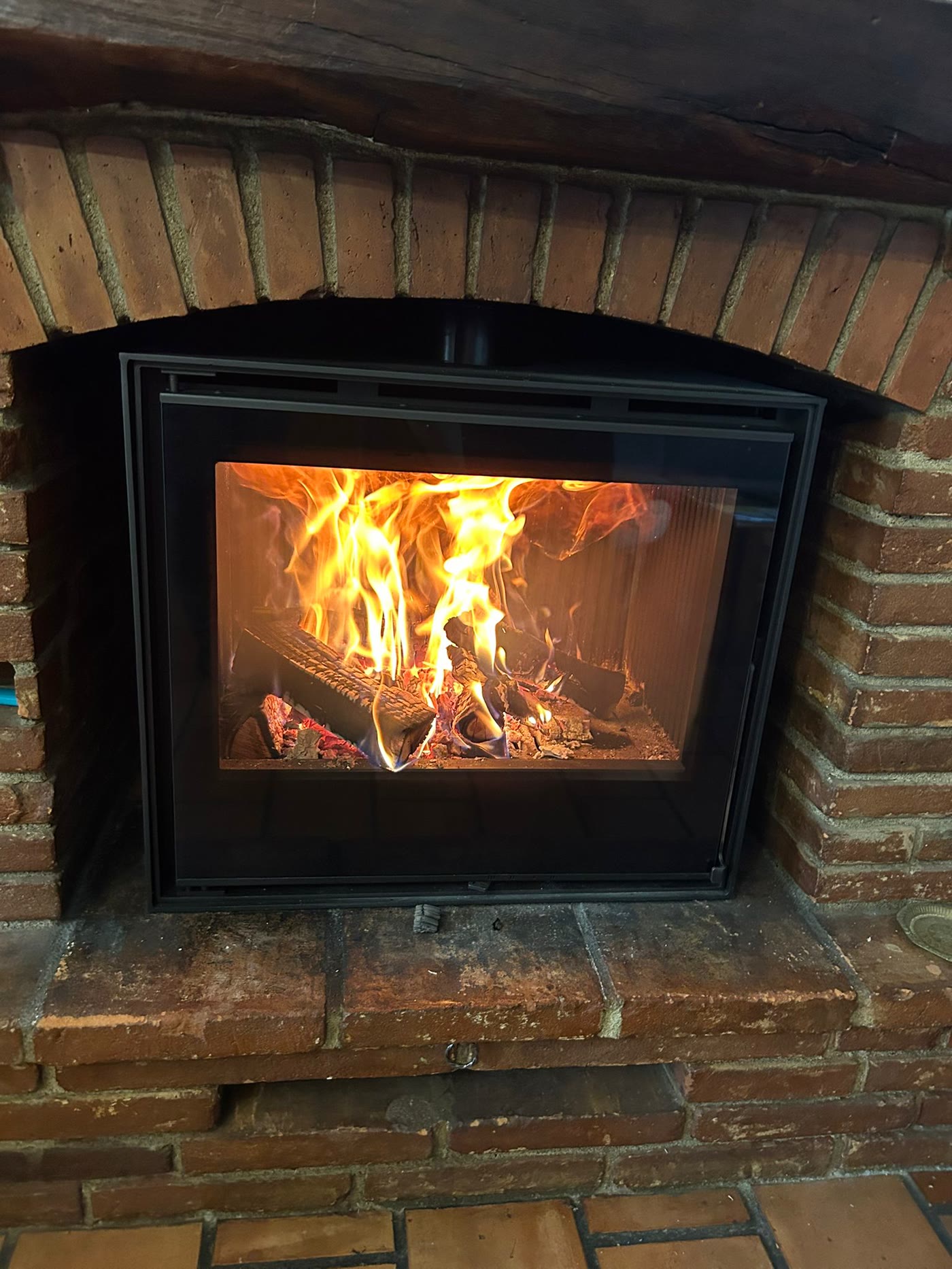 Poêle à bois encastré dans une cheminée en brique